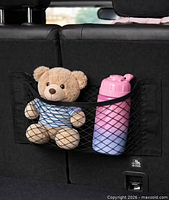 Black elastic mesh cargo net installed, holding stuffed toy and bottle