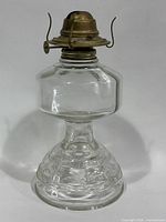 Full view of oil lamp showing glass body and brass burner