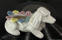 Side view of white ceramic dog planter showing flower accents