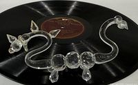 Two-headed faceted crystal dragon figurine displayed on vinyl record for scale