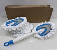 Handle attached to one microfiber head with four additional heads stacked, cardboard box in background
