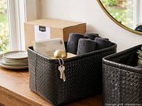 Staged view of one woven bin holding towels and accessories; packaging box visible in background