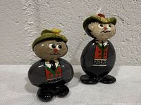 Front view of both hand-painted ceramic Austrian male figurines showing attire and felt hats