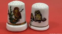 Front view of both porcelain owl thimbles showing illustrations and gold bands