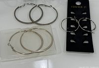Two large hoop earring pairs, small pair on card, plastic case