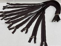 Bundle of approximately 12 dark brown nylon coil zippers with metal sliders