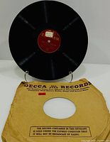 Record on stand showing red Columbia label and brown Decca sleeve