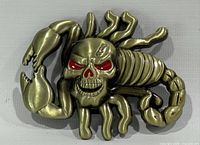 Front view showing full buckle design, brass-tone finish, red eyes