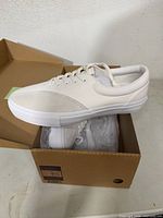 Side view of one sneaker on box showing profile, materials and color