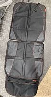 Full view of unfolded Diono two-panel car seat protector showing front mesh pocket and red stitching