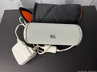 Front view of JBL Flip speaker with charger and carry case