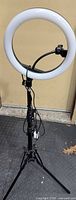 Front view of LED ring light mounted on tripod stand with phone holder and USB cable visible