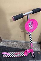 Front view of pink and black striped LOL Surprise folding scooter showing handlebar grips and logo plate