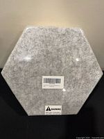 Front of sealed stack of grey hexagon acoustic panel showing texture and barcode