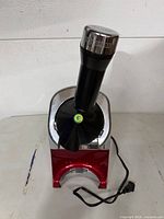 Front view of Yonanas treat maker showing red base, black chute, power cord