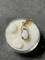 Pendant and two loose opal cabochons in container
