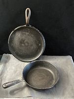 Both cast iron skillets front view showing size difference and handles