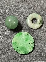 Three jade pieces laid out to show relative sizes and colors