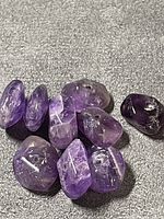 Group of polished amethyst nugget beads showing color range and drilled holes