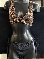 Full view of leopard print top and black bottoms on mannequin