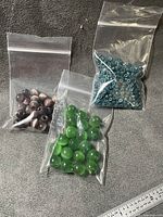 Three bags of assorted beads on grey background with ruler for scale