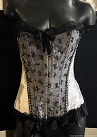 Front view of black & white embroidered corset on mannequin