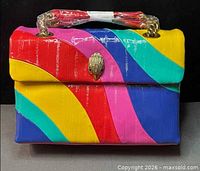 Front view of rainbow patent leather Kurt Geiger shoulder bag with eagle emblem and chain handle wrapped in protective plastic