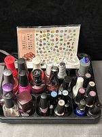 Tray holding assorted nail polish and gel polish bottles, decal sheet, nail tips