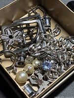 Box containing assorted silver-tone broken jewelry pieces