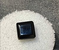 Square black gemstone on white pad showing overall appearance