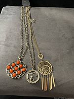Three necklaces laid flat showing pendants and chain styles