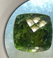Close-up of cushion-cut peridot under magnification showing color and inclusions