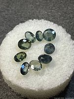 Eight oval blue-green tourmaline gemstones on white foam