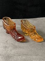 Side view of both amberina glass shoes showing color gradient and pattern