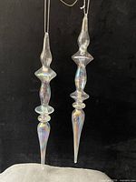 Both glass icicle ornaments hanging against black background