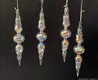 Four iridescent glass icicle ornaments against dark background