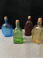 Front view of all four colored Wheaton bottles with corks