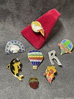 All eight enamel lapel pins displayed on fabric backdrop