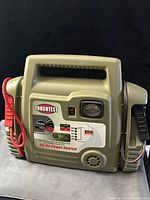 Front view of ToughTest AC/DC power source showing control panel, battery gauge, flashlight, and attached clamps