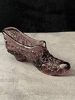 Profile view of amethyst pressed glass shoe showing overall shape and starburst pattern