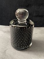 Front angle of cylindrical glass paperweight showing black core with controlled bubbles and clear orb finial
