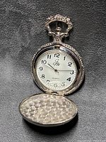 Watch open showing dial, bow, and inner lid pattern