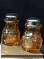 Front view of both shakers showing amber glass color and medallion embossing