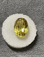 Top view of yellow oval faceted gemstone on white pad