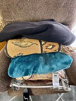 Stacked blankets showing black polar fleece, patterned cotton blend, teal polar fleece and packaging