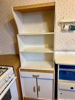Full view of tall white cupboard beside stove