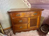Front view of antique ash washstand showing drawers, door, brass hardware