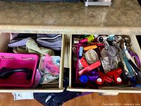 Two open drawers showing towels, baskets, and utensils