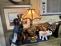 Group view showing lamp base, sculptures, figurines and framed print