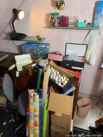 Overall lot view showing gift-wrap rolls, ribbon spools, paint tubes and storage boxes